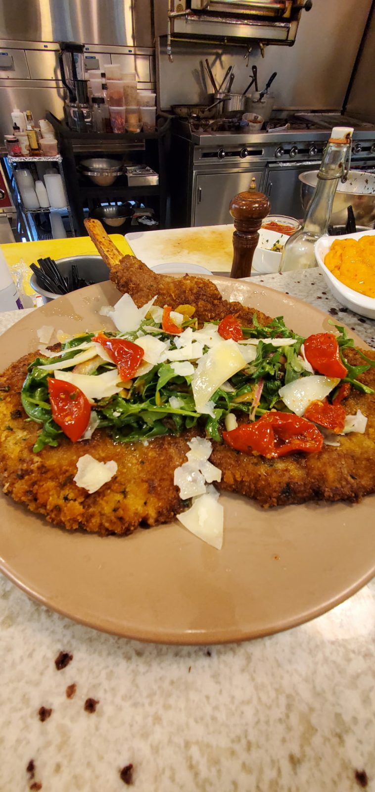 Breaded cutlet topped with arugula, tomatoes and shaved cheese