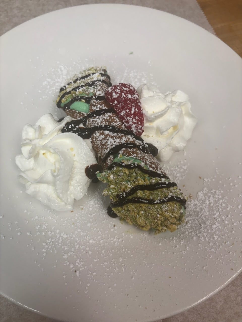 Chocolate-drizzled pistachio cannoli with whipped cream
